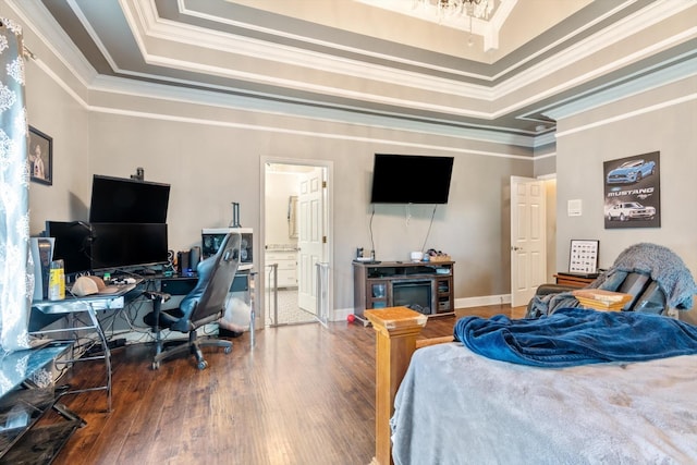 bedroom featuring a tray ceiling, ornamental molding, ensuite bath, and wood-type flooring