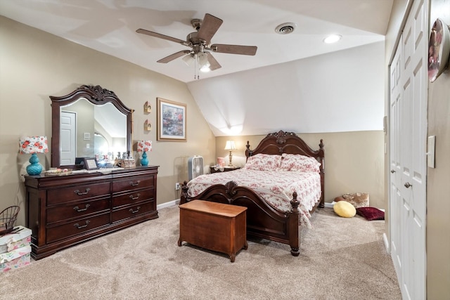 bedroom with ceiling fan, vaulted ceiling, light colored carpet, and a closet