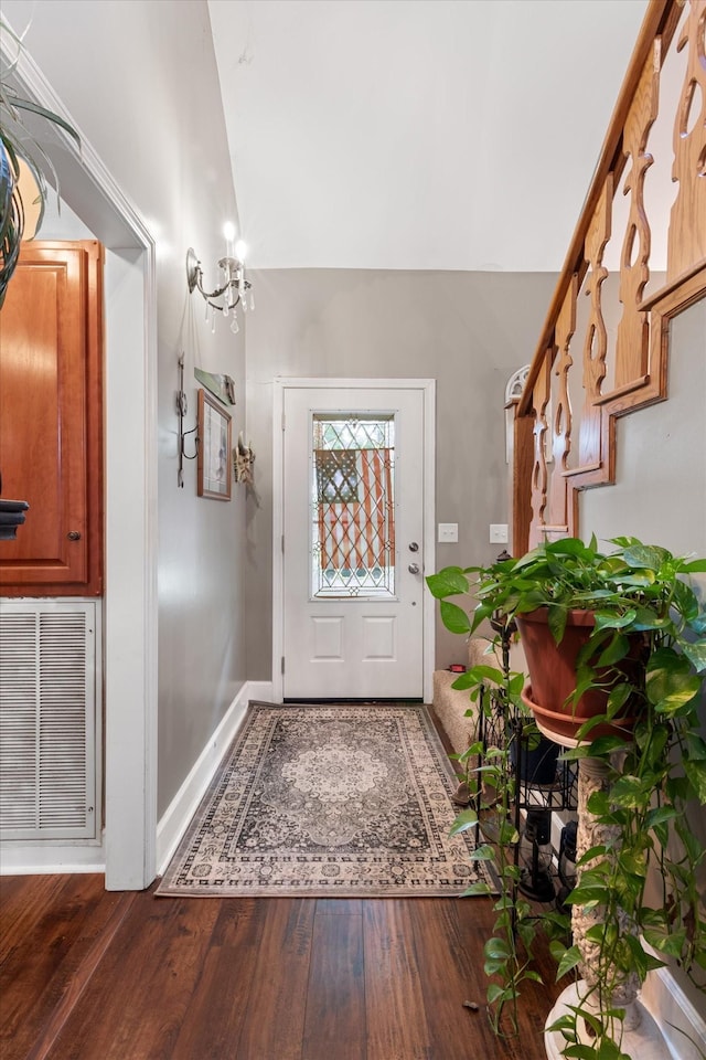 entrance foyer with a notable chandelier, vaulted ceiling, and dark hardwood / wood-style floors