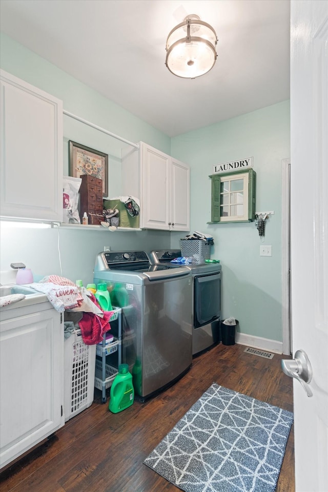 laundry room featuring cabinets, dark hardwood / wood-style floors, and washer and clothes dryer