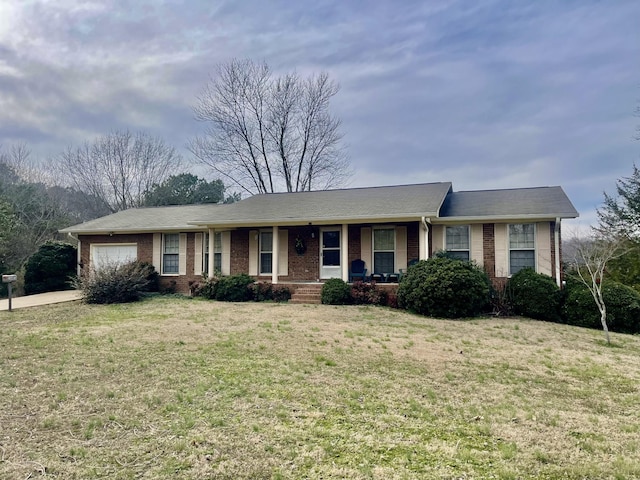 ranch-style house with an attached garage, a front lawn, a porch, and brick siding