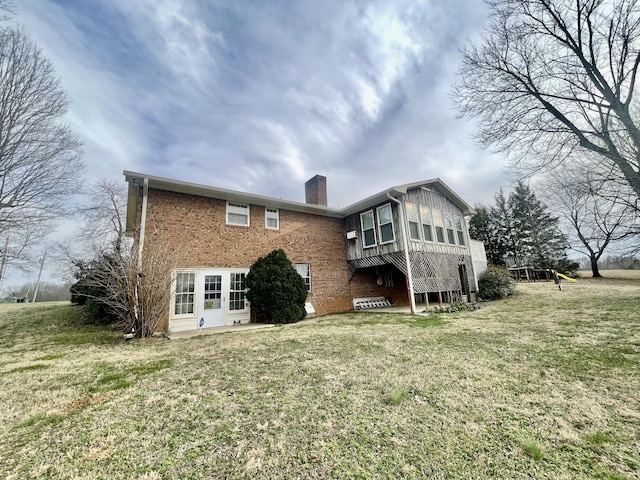 back of property featuring a yard, brick siding, and a chimney