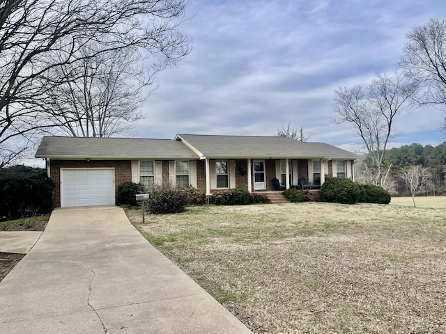 single story home featuring a porch, an attached garage, brick siding, concrete driveway, and a front yard