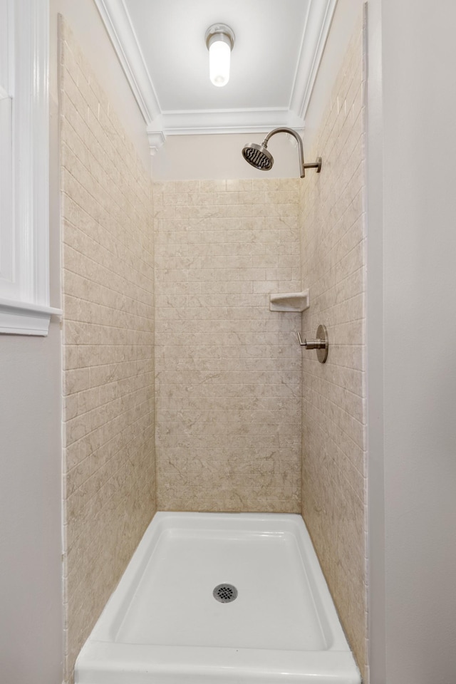 bathroom featuring a tile shower and crown molding