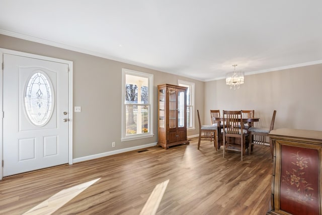 foyer with ornamental molding, an inviting chandelier, and hardwood / wood-style floors