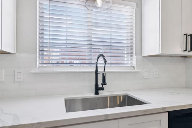 kitchen with white cabinetry, a sink, dishwasher, and light stone countertops