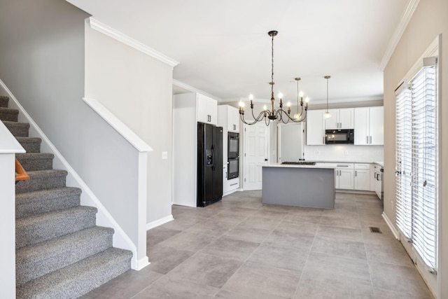 kitchen featuring white cabinets, a kitchen island, light countertops, black appliances, and pendant lighting