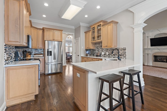 kitchen with kitchen peninsula, a breakfast bar, sink, appliances with stainless steel finishes, and light brown cabinets