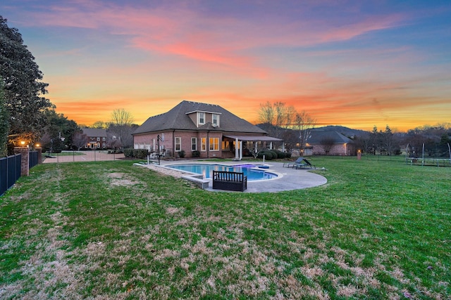 pool at dusk featuring a lawn and a patio area