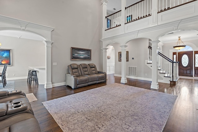 living room featuring dark wood-type flooring, decorative columns, a high ceiling, and ornamental molding