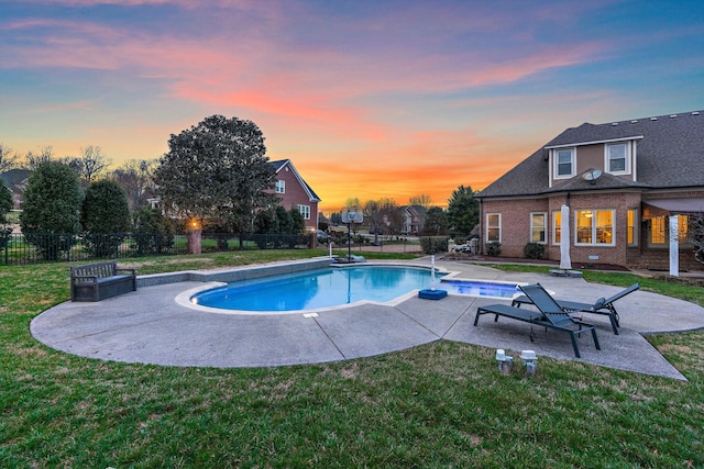 pool at dusk featuring a lawn and a patio area