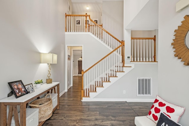 foyer entrance with dark hardwood / wood-style flooring and a towering ceiling