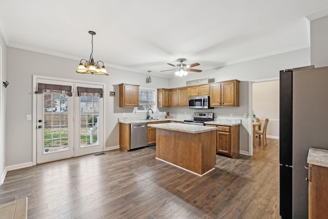 kitchen with appliances with stainless steel finishes, sink, a center island, a healthy amount of sunlight, and hanging light fixtures