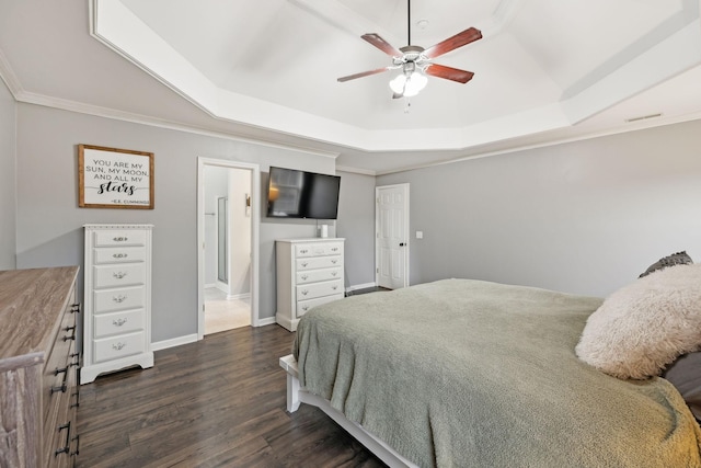 bedroom featuring connected bathroom, dark hardwood / wood-style flooring, a tray ceiling, ornamental molding, and ceiling fan