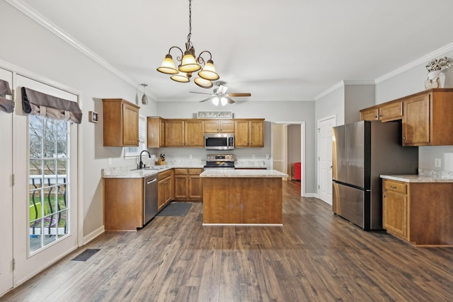 kitchen featuring dark wood-type flooring, stainless steel appliances, a center island, ornamental molding, and sink