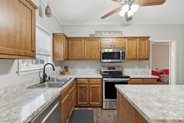 kitchen with appliances with stainless steel finishes, sink, ceiling fan, dark hardwood / wood-style flooring, and ornamental molding