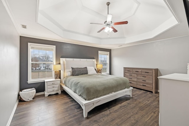 bedroom featuring dark wood-type flooring, a raised ceiling, and multiple windows