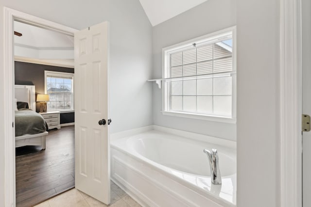 bathroom featuring a bath, vaulted ceiling, and tile patterned floors