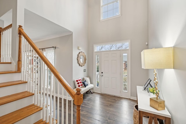 foyer featuring a towering ceiling, crown molding, dark hardwood / wood-style floors, and plenty of natural light