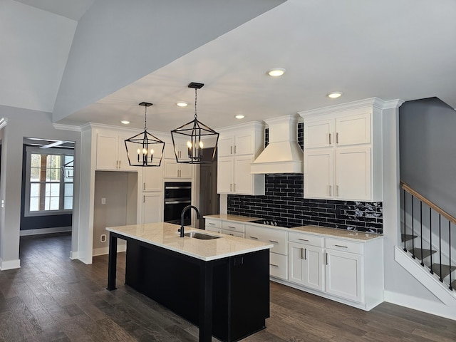 kitchen featuring custom exhaust hood, backsplash, white cabinetry, a sink, and black appliances