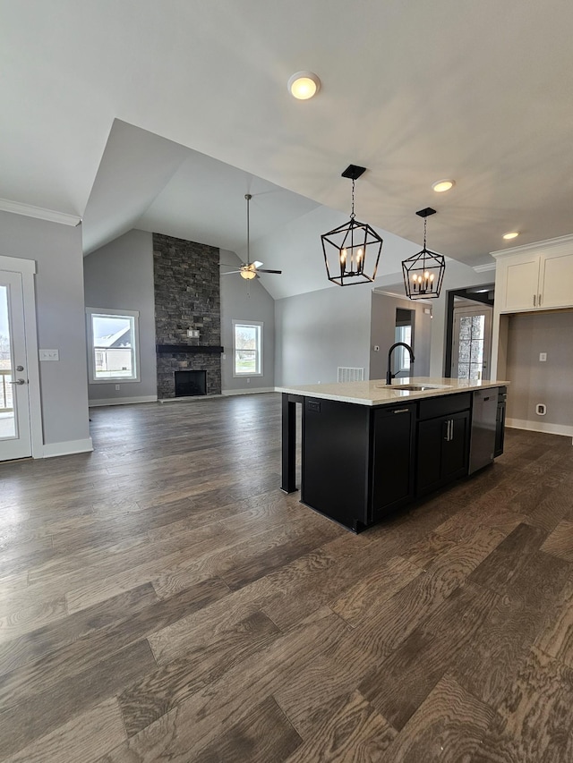 kitchen featuring a wealth of natural light, open floor plan, dark cabinets, a fireplace, and a sink