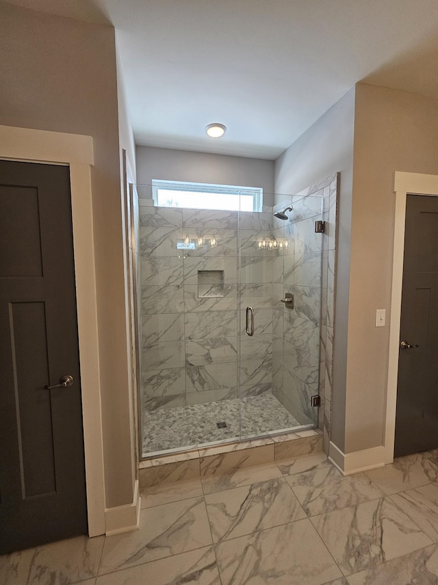 bathroom with a marble finish shower, marble finish floor, and baseboards