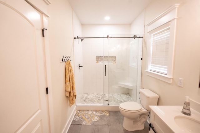 bathroom featuring vanity, toilet, and a shower with door