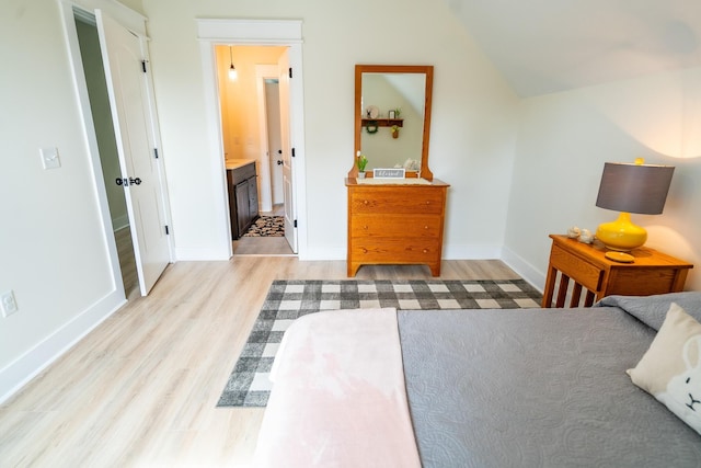 bedroom with lofted ceiling, ensuite bathroom, and light hardwood / wood-style flooring