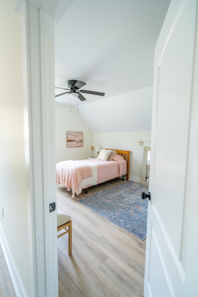 bedroom with ceiling fan, light hardwood / wood-style flooring, and vaulted ceiling