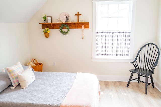 bedroom featuring light hardwood / wood-style floors, vaulted ceiling, and multiple windows