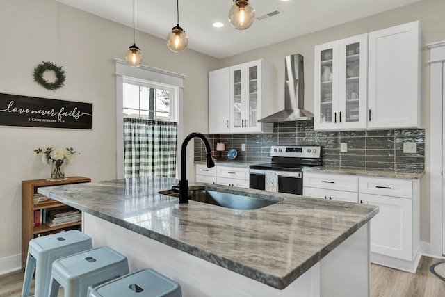 852 Pine Grove Rd, Ringgold, GA 30736 - kitchen with stainless steel range with electric stovetop, wall chimney exhaust hood, a sink, a breakfast bar area, and light wood-style floors