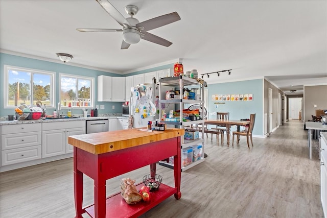 kitchen with sink, stainless steel appliances, white cabinets, and light hardwood / wood-style floors