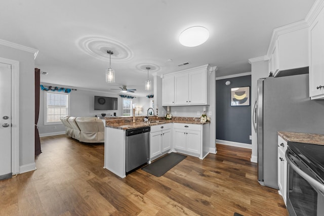 kitchen featuring kitchen peninsula, appliances with stainless steel finishes, white cabinets, crown molding, and pendant lighting