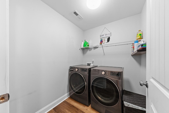 clothes washing area featuring washer and clothes dryer and wood-type flooring