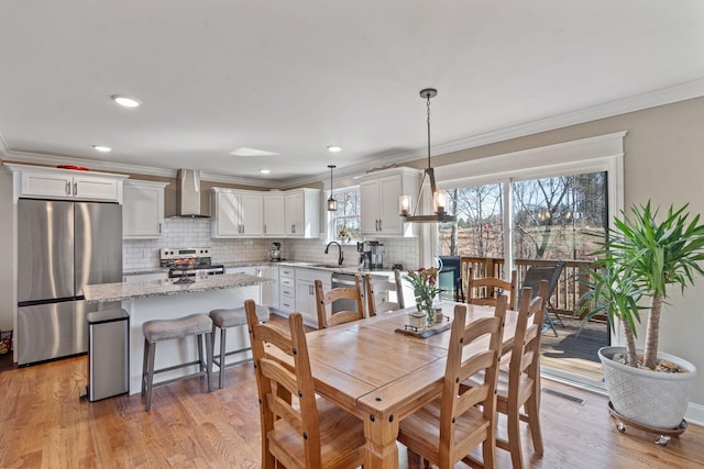 dining area featuring crown molding, light hardwood / wood-style flooring, and sink