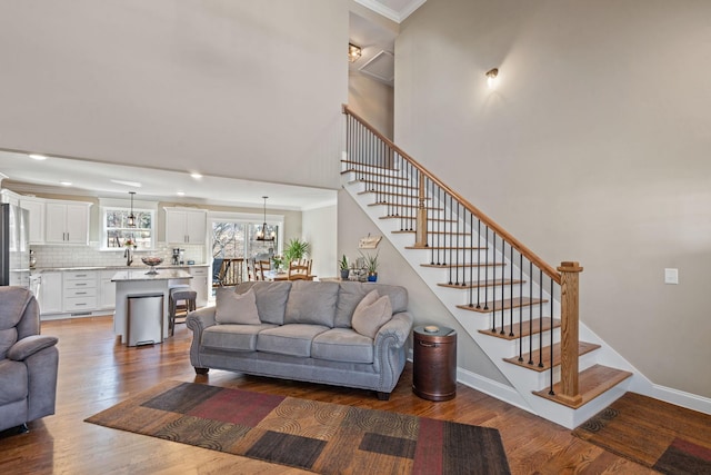 living room featuring hardwood / wood-style floors, an inviting chandelier, sink, a towering ceiling, and ornamental molding