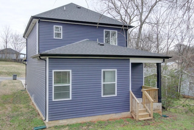 view of side of property with roof with shingles, crawl space, and a yard