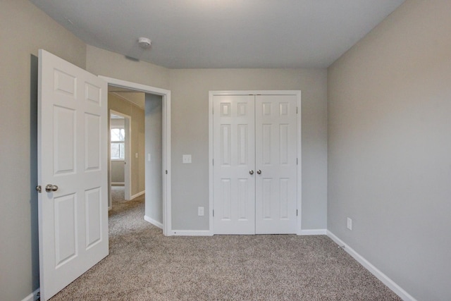 unfurnished bedroom featuring baseboards, a closet, and light colored carpet