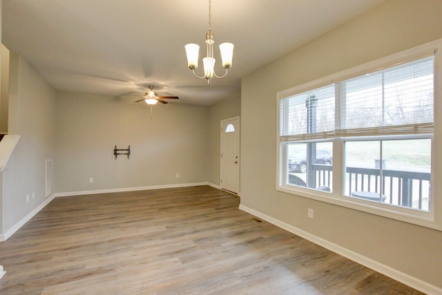 interior space featuring ceiling fan with notable chandelier, baseboards, and light wood-type flooring