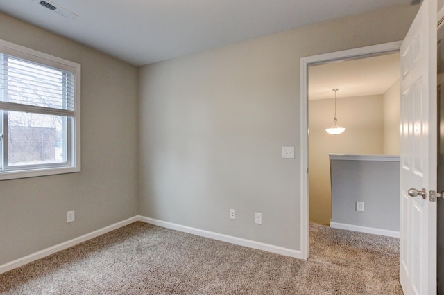 carpeted empty room with baseboards and visible vents