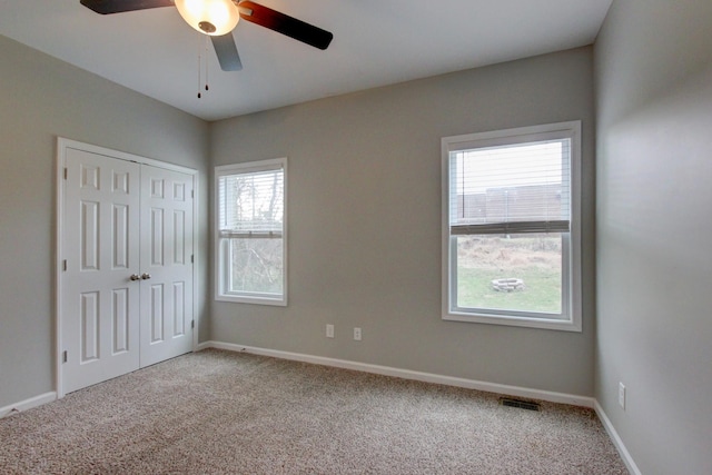 unfurnished bedroom featuring carpet flooring, baseboards, visible vents, ceiling fan, and a closet