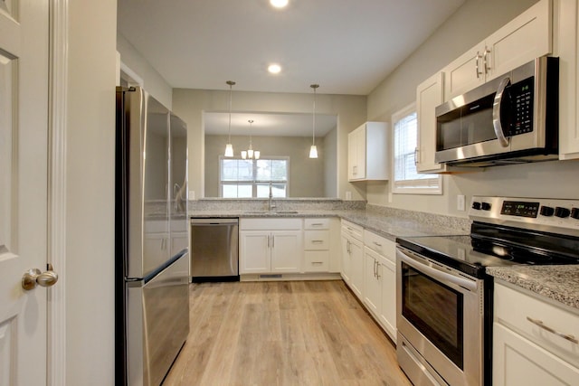 kitchen with light stone counters, white cabinetry, a sink, and appliances with stainless steel finishes