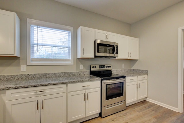 kitchen with light wood-style flooring, baseboards, stainless steel appliances, white cabinetry, and light stone counters