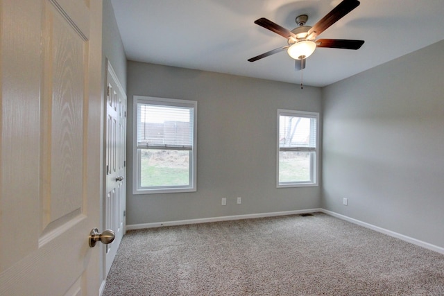 carpeted spare room with baseboards, a ceiling fan, and visible vents