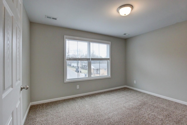 spare room with carpet flooring, baseboards, and visible vents