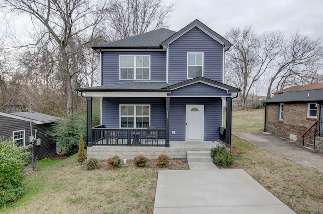 view of front of property with roof with shingles, a front lawn, and covered porch