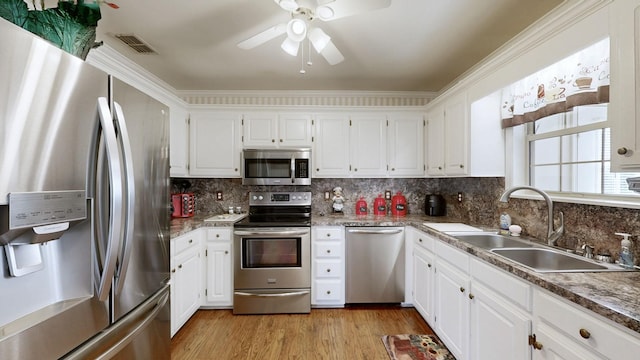 kitchen featuring visible vents, white cabinetry, a sink, light wood-type flooring, and stainless steel appliances