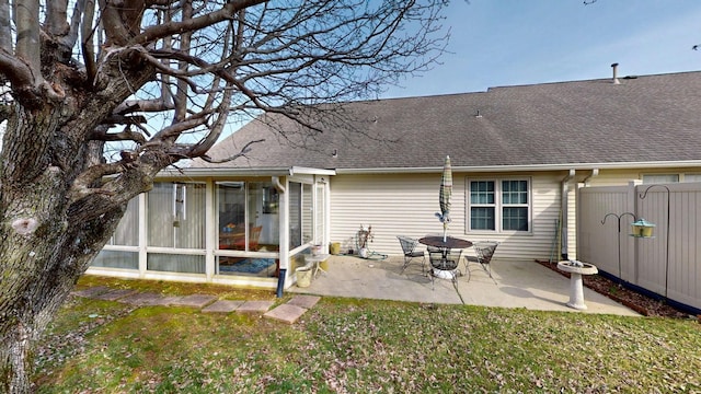 back of house featuring a sunroom, a yard, roof with shingles, and a patio area