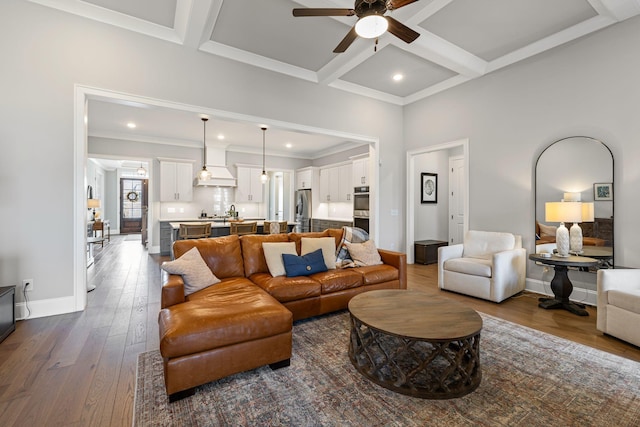living room featuring wood finished floors, a ceiling fan, baseboards, coffered ceiling, and beamed ceiling
