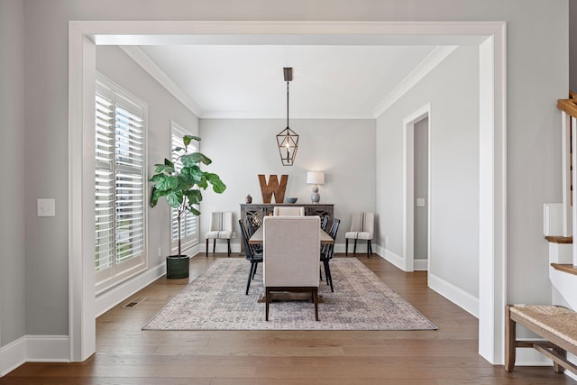 dining area with baseboards, visible vents, wood finished floors, and ornamental molding